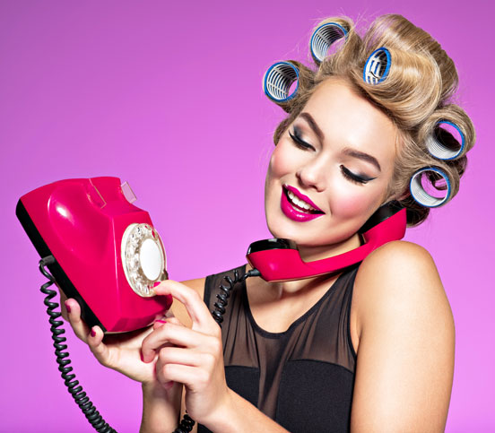 young woman making a phone call on a rotary-dial phone